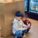 Children watching a smartphone together in a shop, illustrating young people and mobile content