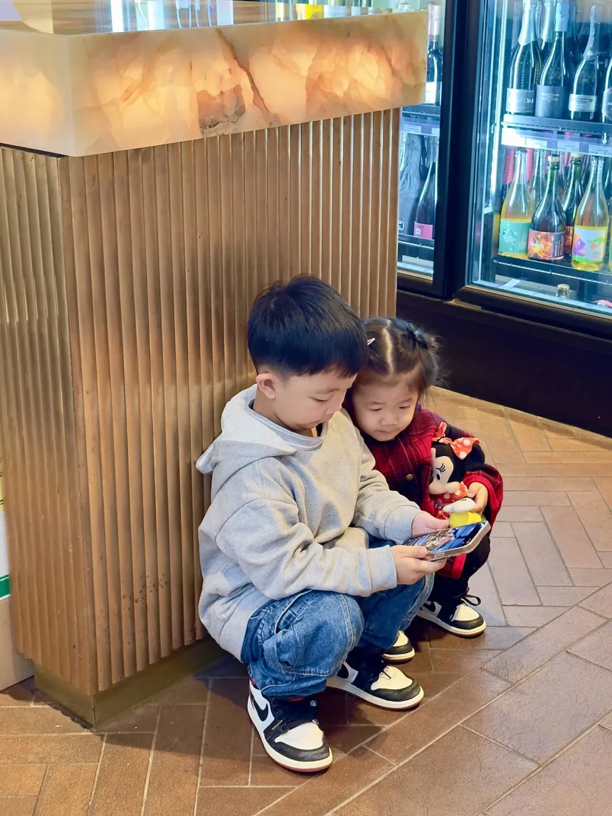 Children watching a smartphone together in a shop, illustrating young people and mobile content
