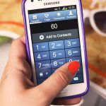 A shopper pays at a checkout by holding a smartphone near a payment terminal.