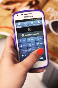 A shopper pays at a checkout by holding a smartphone near a payment terminal.