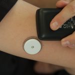 Person scanning a continuous glucose monitor sensor worn on the arm