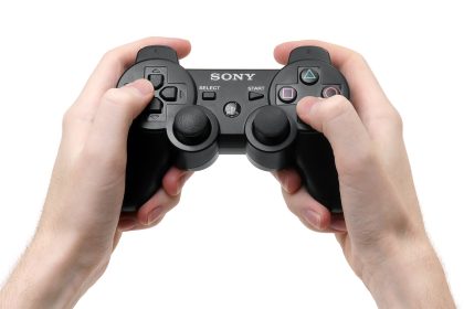 Hands gripping a Sony DualShock controller against a white background